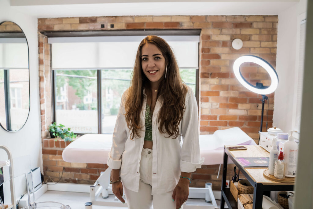 A woman in a white coat standing in front of a mirror.